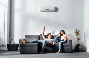 man-and-woman-sitting-on-couch-changing-temperature-of-mini-split
