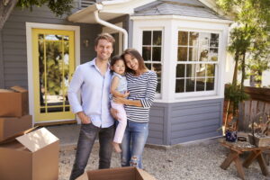 family-standing-in-front-of-home-with-moving-boxes