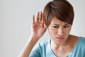 woman-holds-hand-up-to-ear-trying-to-hear-