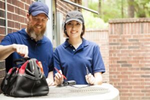 male-and-female-HVAC-technicians-working-on-condenser-